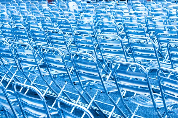 青い光の中で空の金属製の椅子席の行 — ストック写真