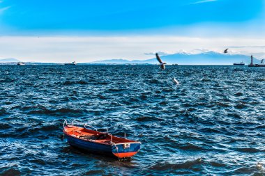 dağlar ve deniz feneri ile dalgalı denizde boş balıkçı teknesi