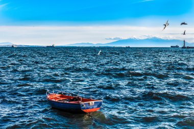 dağlar ve deniz feneri ile dalgalı denizde boş balıkçı teknesi