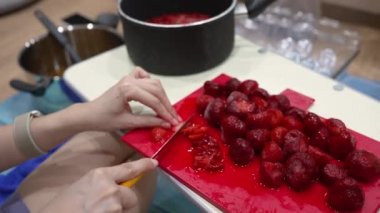 Mutfakta tatlı yapmak için çilek doğrayan şefin eli.