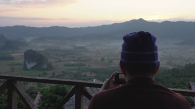 Tatil sırasında gün doğumunun fotoğrafını çeken bir adamın portresi.