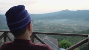 Sabahları dağ manzarasına bakan genç bir adamın portresi