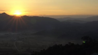 Dağların ardında güzel bir gün doğumu manzarasını büyüt