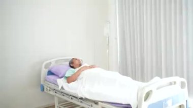 Asyalı doktor hastane koğuşundaki kıdemli hastayla konuşuyor.