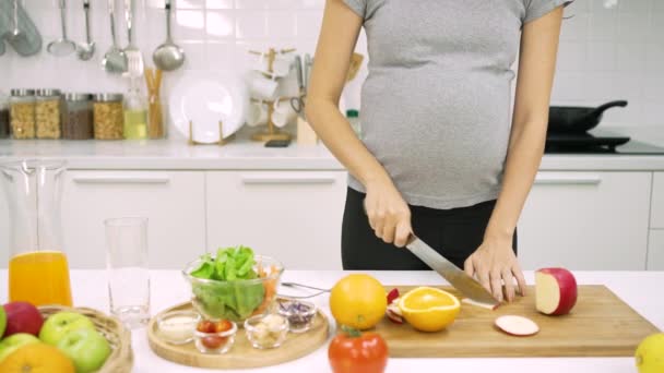 夫がキッチンを歩いている間に健康的な朝食を準備妊娠中の女性 — ストック動画