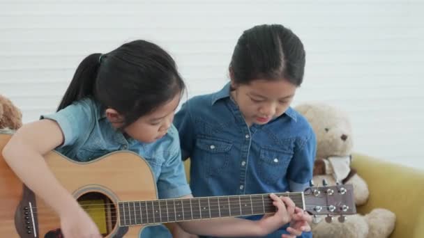 Asiática Mayor Hermana Enseñando Más Joven Hermana Tocar Guitarra Casa — Vídeo de stock