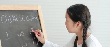 Banner Picture of Asian Girl Writing Chinese Alphabets on Blackboard in Classroom