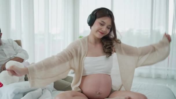 Asiatisk Gravid Kvinna Lyssna Musik Medan Maken Leker Med Dottern — Stockvideo