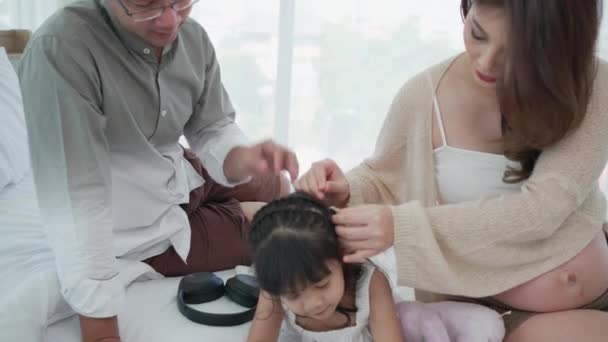 亚洲怀孕妇女在家中结着女儿的头发 与丈夫坐在一起 — 图库视频影像