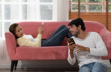 Orta Doğulu bir adam oturma odasında Asyalı bir kadınla konuşuyor ve akıllı telefon kullanıyor. Karışık Irk Aile Kavramı