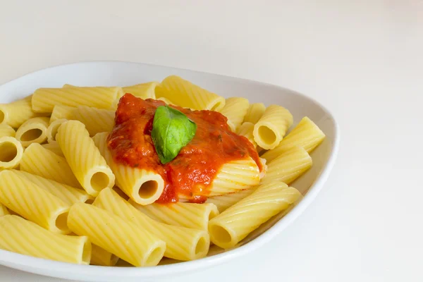 Macarrones italianos con salsa de tomate y hojas de albahaca — Foto de Stock