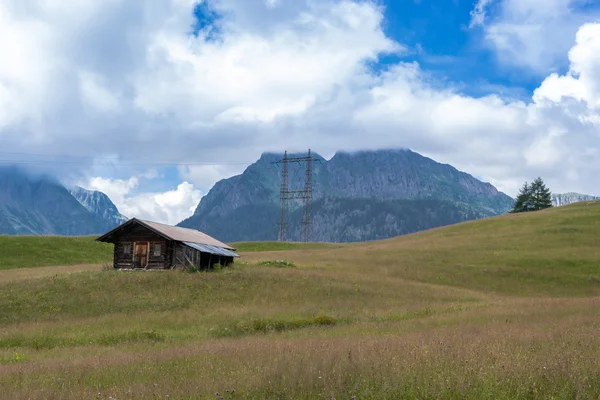 Casa de madera en un prado verde cerca de las montañas — Foto de Stock