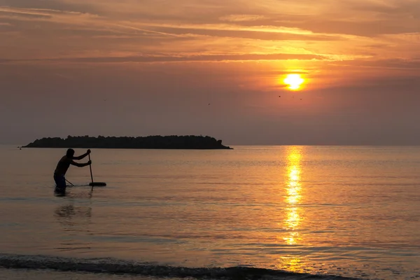 Homem de pesca no mar durante o nascer do sol — Fotografia de Stock