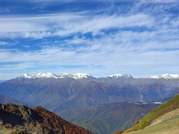 Snow on mountain tops under a blue sky on a clear autumn day