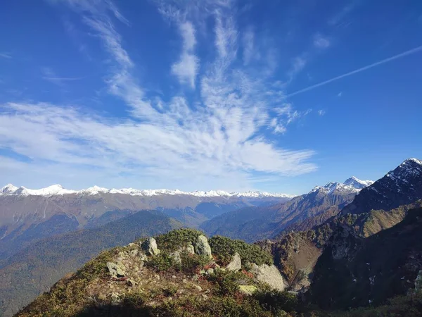 Snow on mountain tops under a blue sky on a clear autumn day