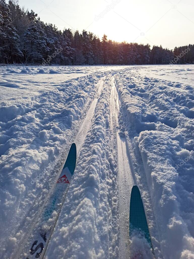 A ski run on a frozen lake among snow on the background of the setting sun.