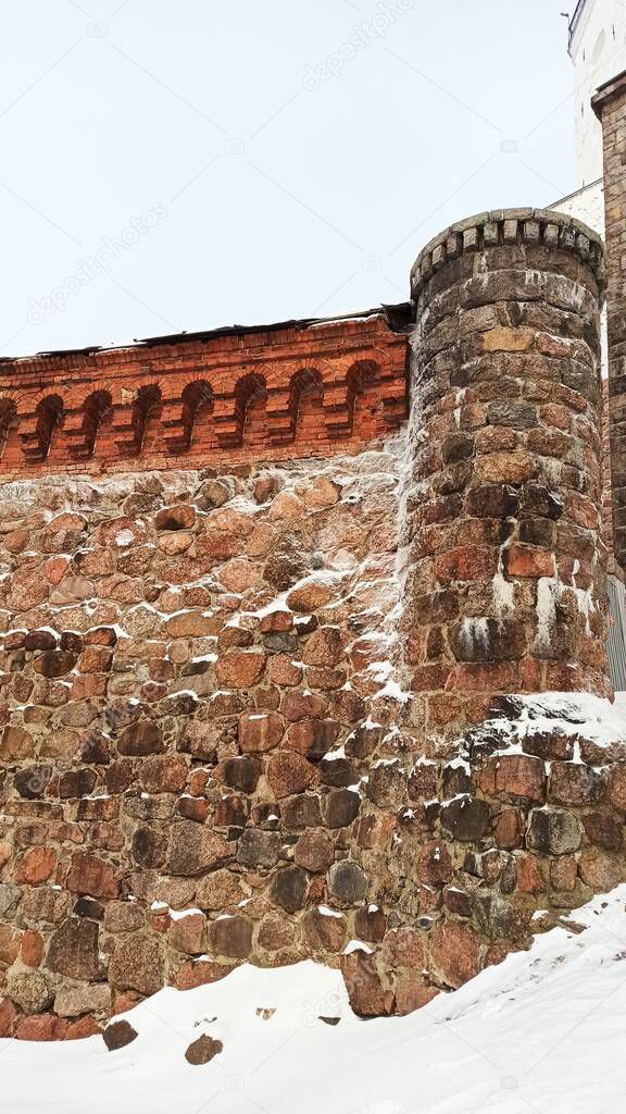 Stone fortress wall of an old castle with narrow windows in Vyborg on a sunny winter day