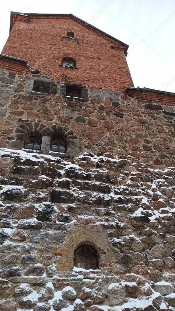 Stone fortress wall of an old castle with narrow windows in Vyborg on a sunny winter day