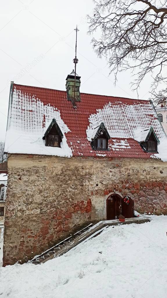 Stone medieval house with a red tiled roof and snow on it in the historic city of Vyborg