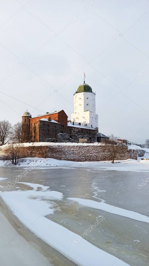 An ancient medieval castle-fortress with a tower located on an island among ice and snow in Vyborg on a sunny winter day