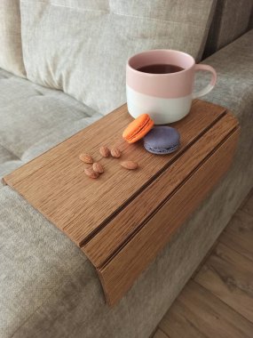 Kanepenin koltuğu için ahşap bir standın üzerinde kurabiye ve fındıklı büyük bir kupa çay..