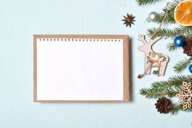 Boş bir kartpostal, soluk mavi bir arkaplanda, bir kraft zarfının üzerinde duruyor. Pankart, davetiye, plan, kartpostal. Flatlay, Flatlay, Flatlay, Top View, Top View