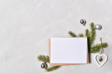 Gri arka plandaki bir Noel ağacının dallarına bir zarf. Üst görünüm.