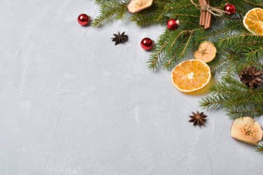 Gri arka planda turuncu, anason ve cam kırmızı toplu köknar dallarının Noel kompozisyonu. Düz yatış, üst görünüm