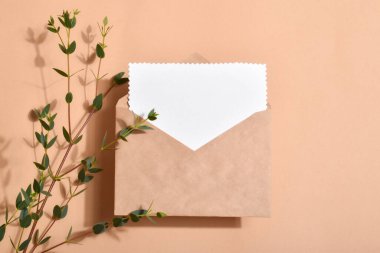 Bej arkaplanlı ve okaliptüslü bir zarfın asgari yerleşimi. Mesaj için boş bir kart. Davet.