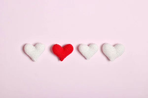 Cztery szydełkowane serca z rzędu leżą na czerwonym tle. Kontekst Walentynki. — Zdjęcie stockowe