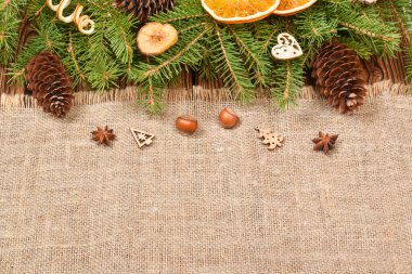 Doğal takılardan yapılmış Noel kompozisyonu. Portakal ve kozalaklı, yırtık pırtık doğal kumaş ve ladin dalları. Uzayı kopyala Düz yatış, üst görünüm. 