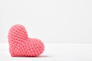 Pembe bir kalp beyaz bir ahşap masanın üzerinde yatıyor. Sevgililer Günü için arkaplan