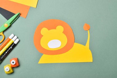 DiY aslanı. Renkli kağıttan aslan yaparız. Adım adım talimatlar. Üçüncü adım, ağızlığı ve kuyruğu yapıştır. Düz yatış, üst görünüm