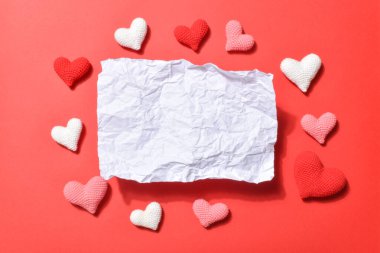 Kırışmış bir kağıt parçası. Gölgesi ve kırmızı arka planda boş bir yer. Kalpleri örülmüş. Buruşmuş kağıt desenli boş bir afiş. Uzayı kopyala Düz yatış, üst görünüm.