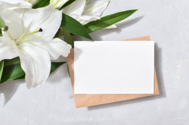 Şablon boş bir kağıt ve üzerinde nilüfer çiçekleri olan gri bir arkaplanda yazı için yer olan bir zarf. Düz görünüm, kopyalanacak bir yer.