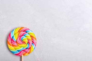 Gri bir arka planda renkli bir lolipop. Tatlı tatlı. Şekerleme arka planı. Kopyalamak için yer var. Düz konum, üst görünüm.