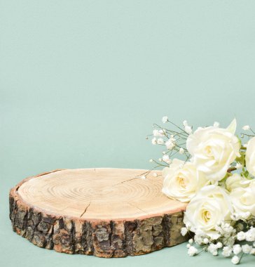 Ürün sunumu için podyum. Kesilmiş bir ağacın beyaz güllerle minimalist bir sahnesi. Sergi için vitrin..