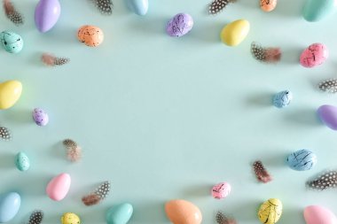 Paskalya kartpostalında yatak boyalı yumurtalar ve mekanın bir kopyası var. Boyalı yumurta ve tüy çerçevesi. Uzayı kopyala Düz yatış, üst görünüm.