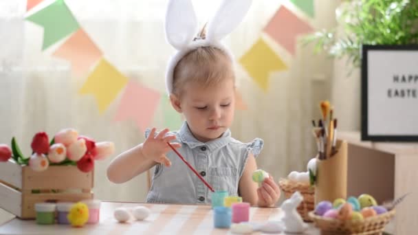 Uma menina de dois anos desenha ovos de Páscoa. — Vídeo de Stock