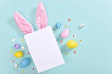 Tavşan kulaklı arka plan ve boş bir kağıt parçası ve paskalya yumurtaları..