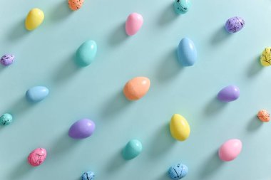Açık mavi arka planda pastel renklere boyanmış yumurtalar. Paskalya 'nın minimum kompozisyonu. Yumurtalı bir tatil kartı. Boşluğu kopyala
