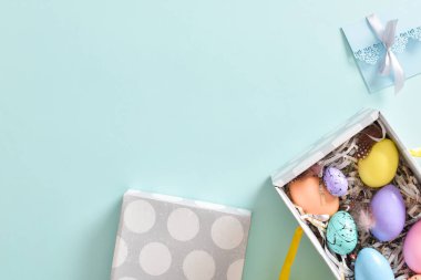 Paskalya yumurtaları tavşan kulakları ve mavi zarfın yanındaki bir kutuda. Paskalya bayrağı. Davetiye için şenlik arka planı. Kopyalamak için yer var. Düz konum, üst görünüm.