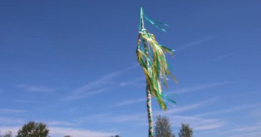 Maypole with a wreath and colorful ribbons fluttering in the summer wind