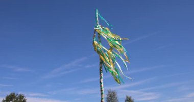 Maypole with a wreath and colorful ribbons fluttering in the summer wind