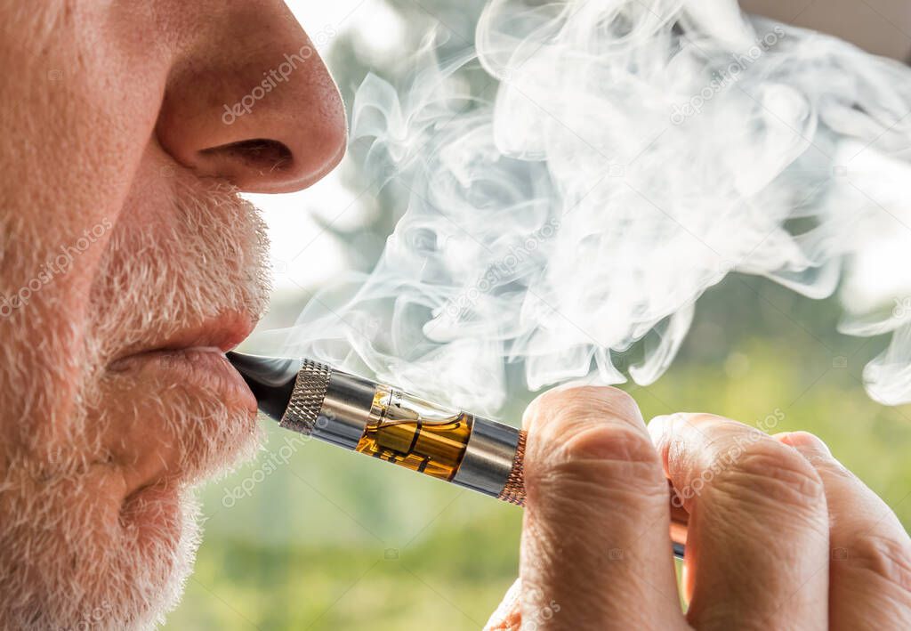 Close-up of adult senior man smoking electronic cigarette.