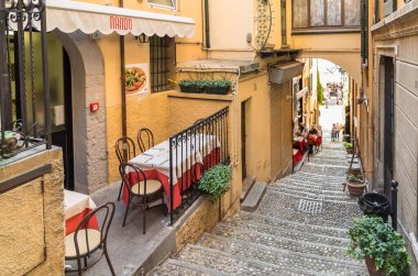 Bellagio, Lombardy, İtalya - 5 Eylül 2022: Como Gölü üzerindeki küçük pitoresk köy Bellagio 'da açık hava konforlu sokak restoranı.