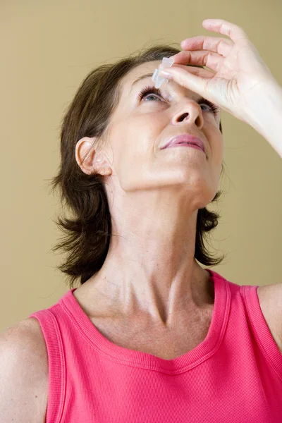 Äldre person som använder eye lotion — Stockfoto