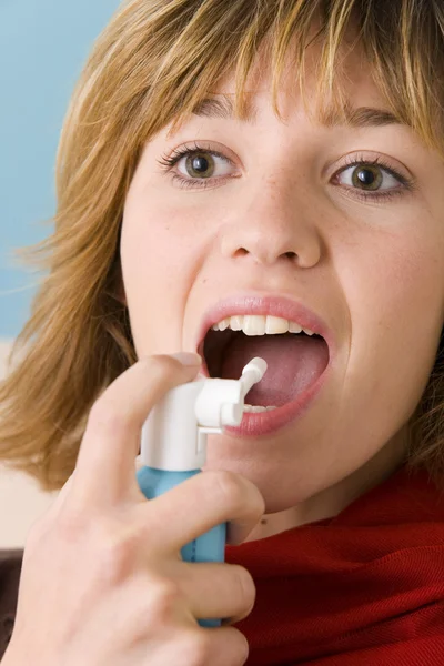 Vrouw met behulp van spray in mond — Stockfoto