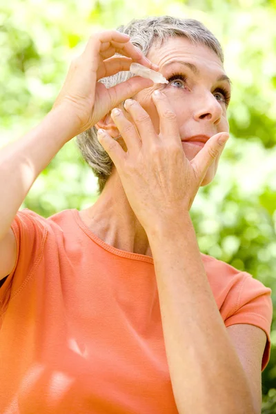 Bejaarde gebruik van oog lotion — Stockfoto