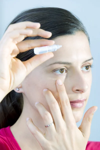 Vrouw met behulp van oog lotion — Stockfoto